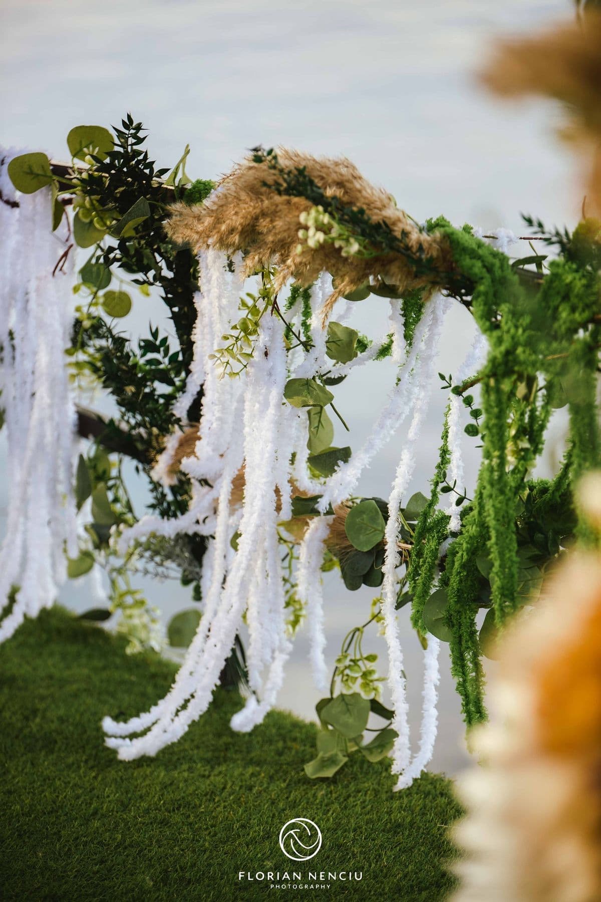 Ghirlande albe și verdeață atârnate de arcada de ceremonie
