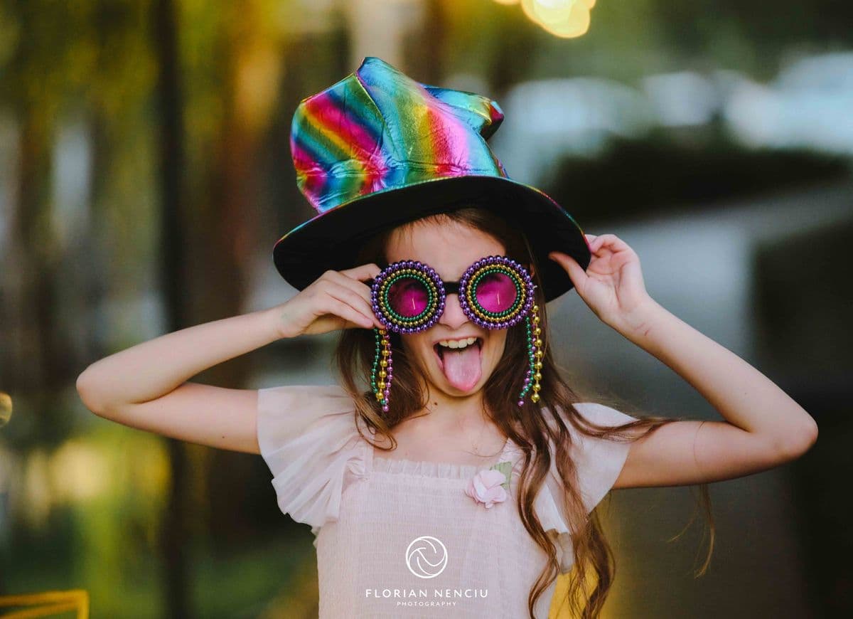 O fetiță cu joben colorat și ochelari mari din recuzita oglinzii foto